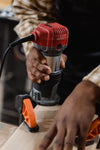 Woodworker using a compact router on a wooden board
